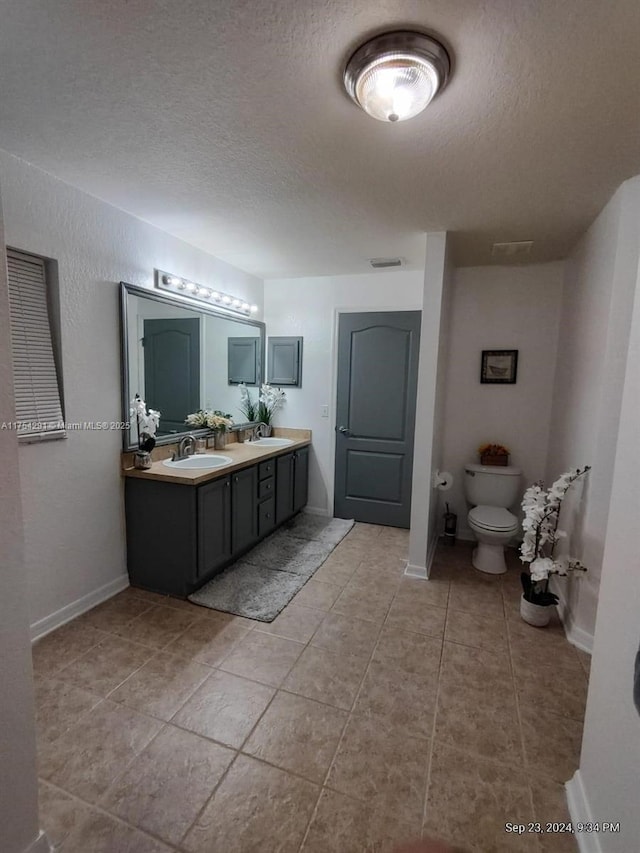 bathroom with a textured ceiling, a sink, and toilet