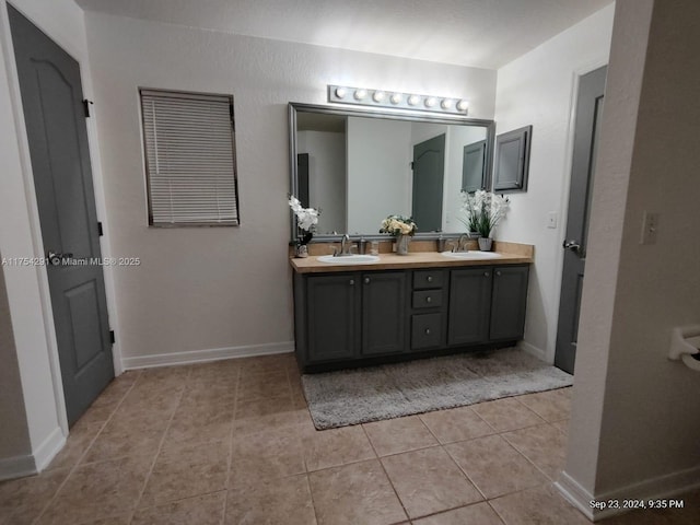 full bath with a sink, baseboards, double vanity, and tile patterned flooring