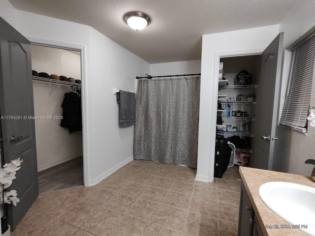 bathroom with a shower with shower curtain, vanity, a textured ceiling, and tile patterned flooring