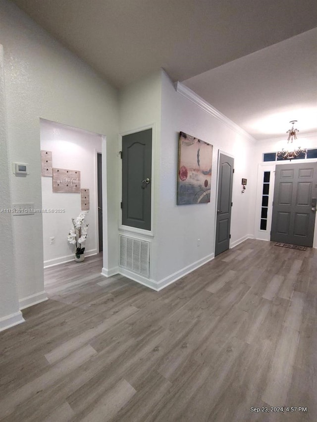 foyer entrance with baseboards, wood finished floors, a notable chandelier, and visible vents
