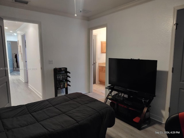 bedroom with baseboards, light wood-style flooring, ensuite bathroom, crown molding, and visible vents