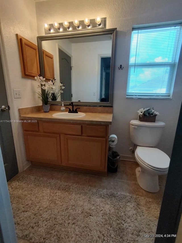 bathroom with toilet, tile patterned floors, and vanity