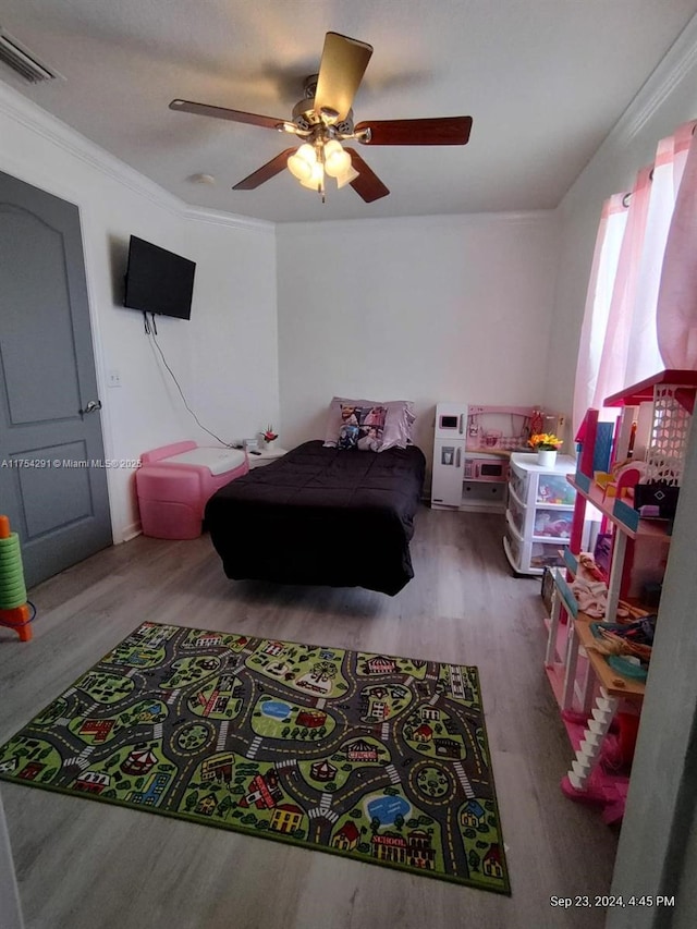 bedroom featuring visible vents, crown molding, a ceiling fan, and wood finished floors