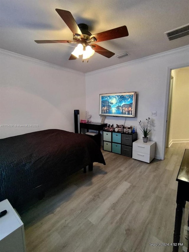 bedroom with crown molding, visible vents, and light wood-style floors