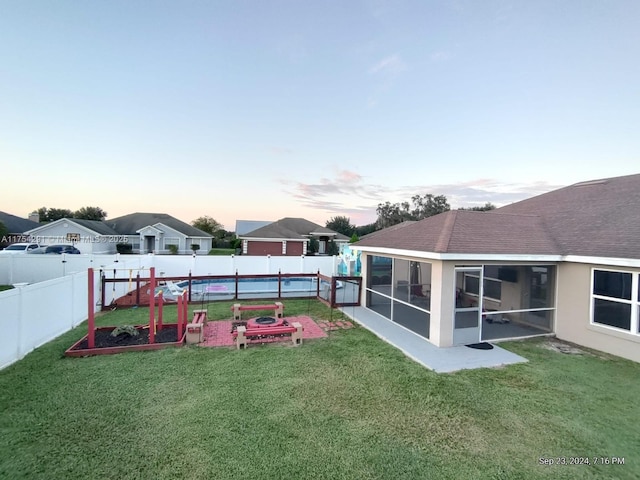 yard at dusk with a sunroom, a fenced backyard, and a garden