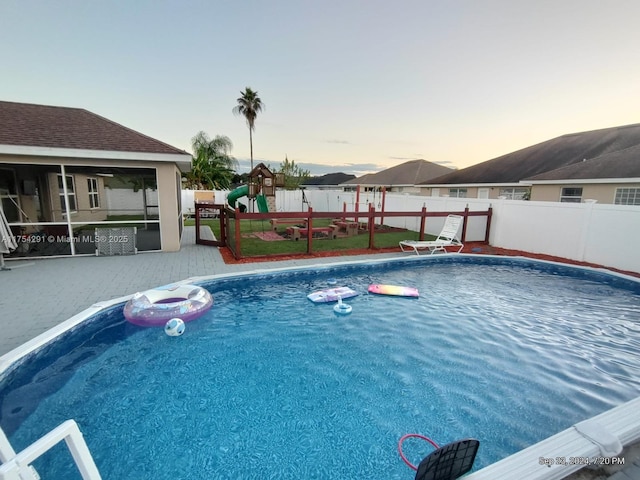 view of pool with a fenced backyard, a playground, a fenced in pool, and a patio
