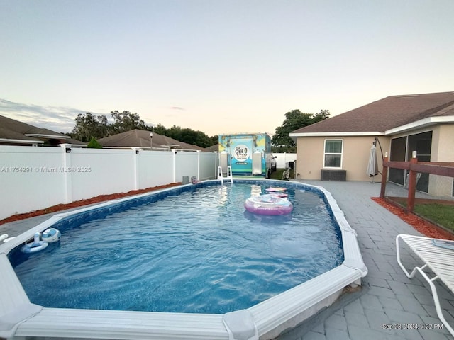 pool at dusk featuring a fenced in pool, a patio area, and a fenced backyard