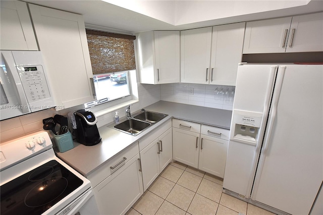 kitchen featuring white appliances, tasteful backsplash, light tile patterned floors, white cabinetry, and a sink