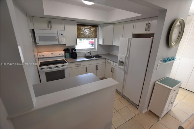 kitchen with white appliances, decorative backsplash, a peninsula, a sink, and light tile patterned flooring