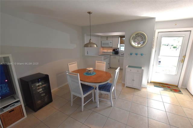 dining space featuring a wealth of natural light, wine cooler, a textured ceiling, and light tile patterned floors