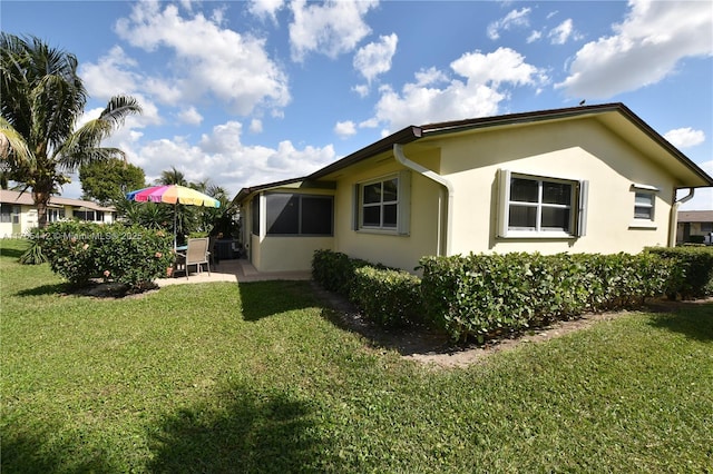 view of side of home with a yard, a patio, and stucco siding