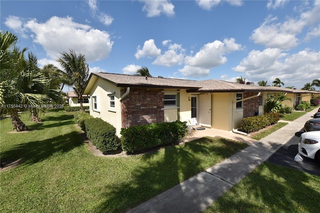 view of front of home featuring brick siding, a front yard, and stucco siding