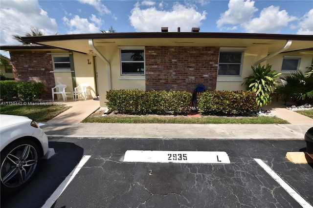 view of front of house with uncovered parking and brick siding