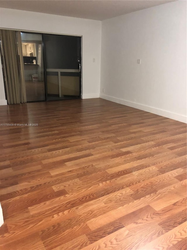 spare room with baseboards and wood finished floors