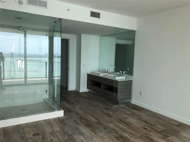 bathroom featuring double vanity, a stall shower, wood finished floors, and visible vents