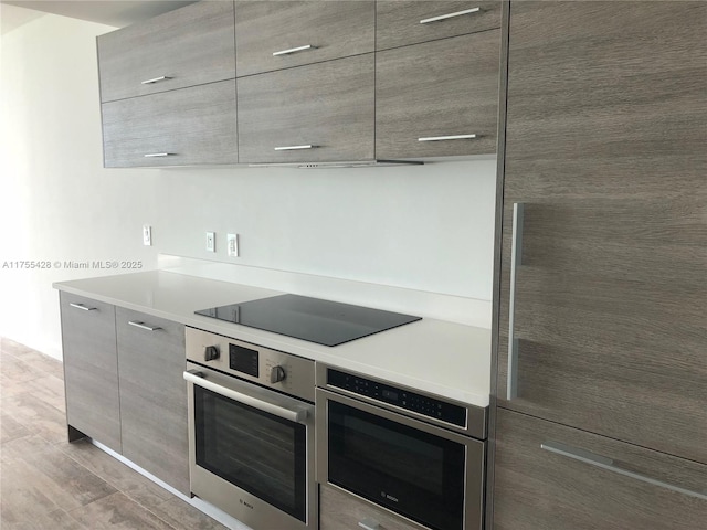 kitchen with modern cabinets, black electric cooktop, light countertops, and oven