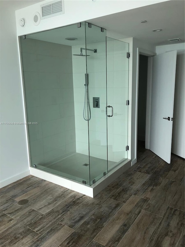 bathroom with a shower stall, visible vents, and wood finished floors