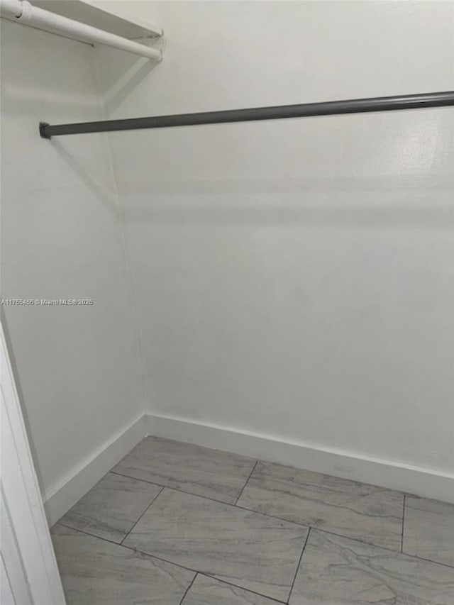 walk in closet featuring marble finish floor