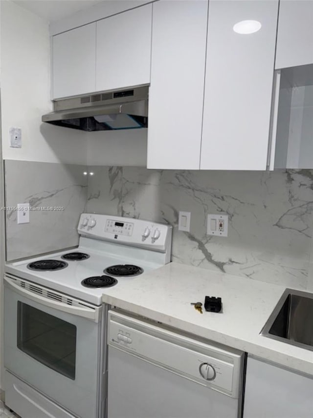 kitchen with white appliances, white cabinetry, under cabinet range hood, and decorative backsplash