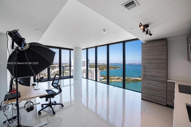 office area featuring light tile patterned floors, a wall of windows, a water view, and visible vents