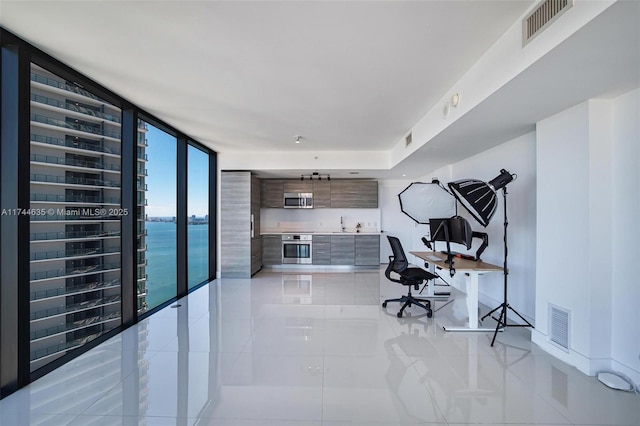 office area featuring light tile patterned floors, visible vents, and a wall of windows