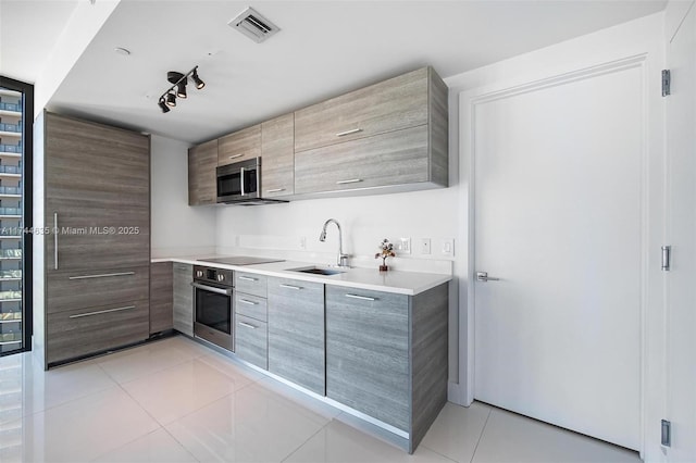 kitchen with visible vents, modern cabinets, appliances with stainless steel finishes, a sink, and light tile patterned flooring