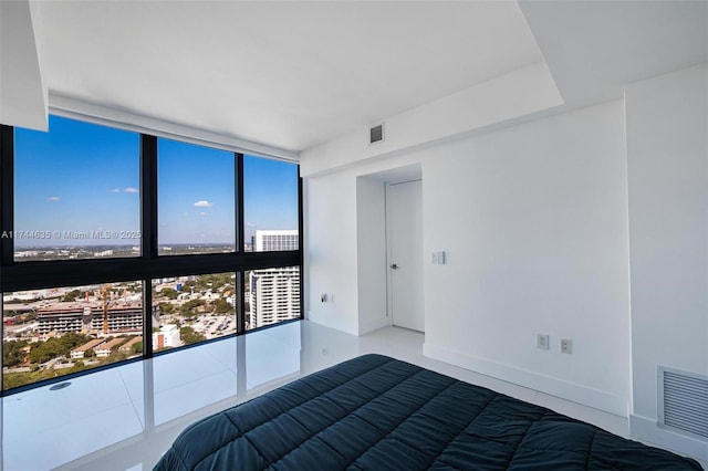 unfurnished bedroom with baseboards, a view of city, visible vents, and floor to ceiling windows