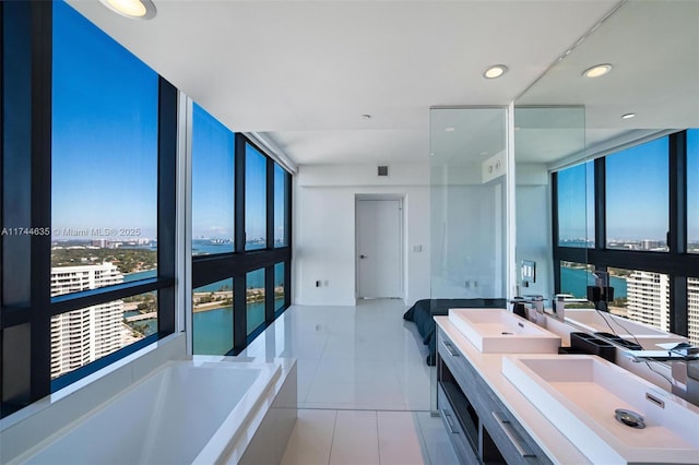 bathroom featuring a garden tub, expansive windows, a sink, and tile patterned floors