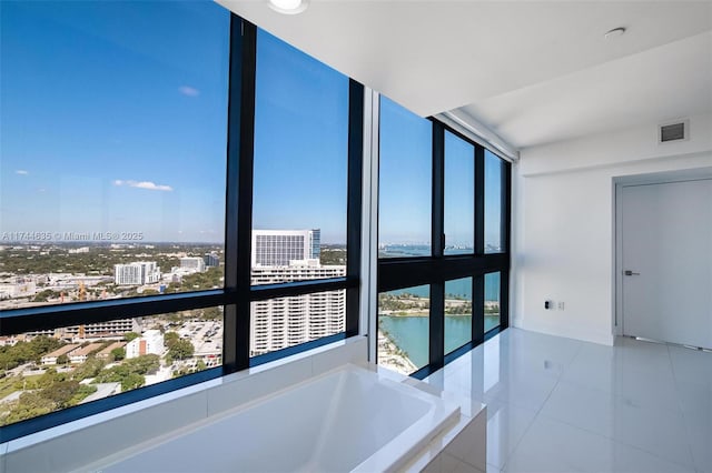 interior space featuring a water view, tile patterned flooring, visible vents, and a city view