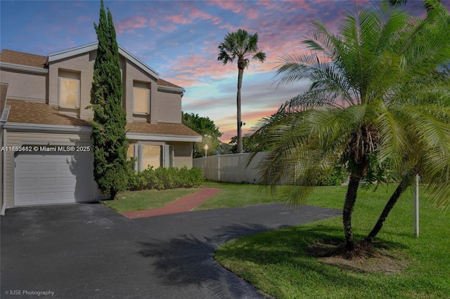 view of front of house with a front yard, fence, driveway, and stucco siding