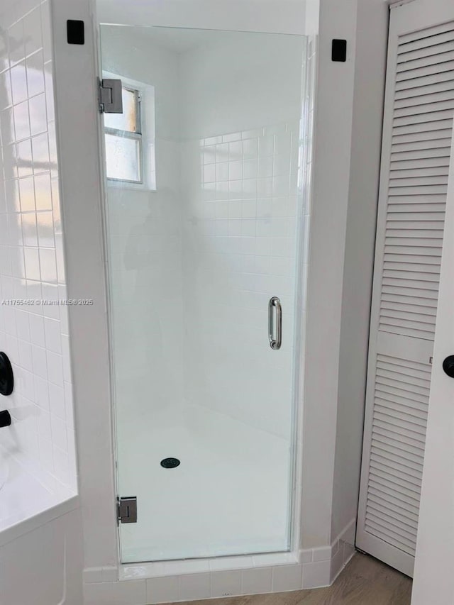 full bath featuring a stall shower, baseboards, a closet, and wood finished floors