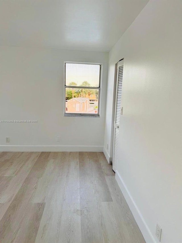 spare room with light wood-style floors and baseboards