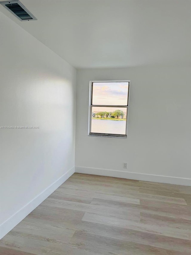 unfurnished room with visible vents, light wood-style flooring, and baseboards