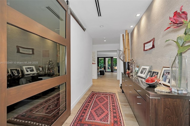 hall featuring french doors, light wood-style flooring, and baseboards