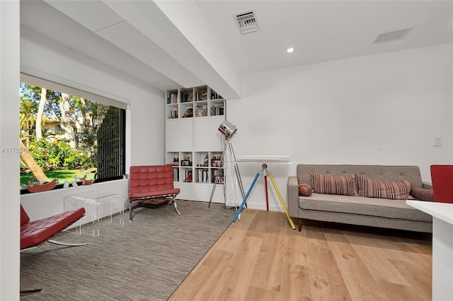 living area featuring visible vents and wood finished floors