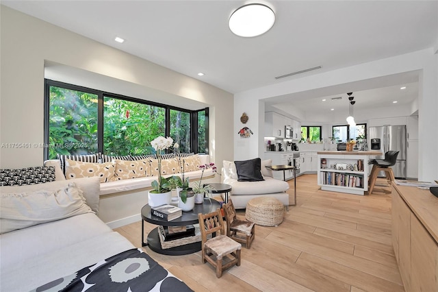 living room with light wood-type flooring, visible vents, and recessed lighting