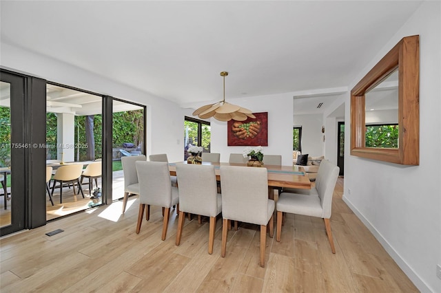 dining room with light wood finished floors, visible vents, and baseboards