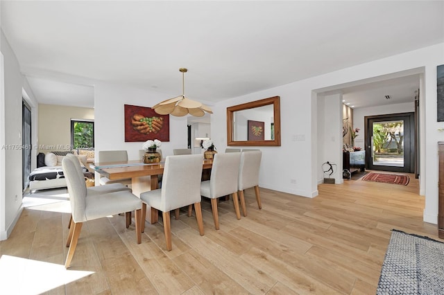 dining area featuring light wood-type flooring, a wealth of natural light, and baseboards