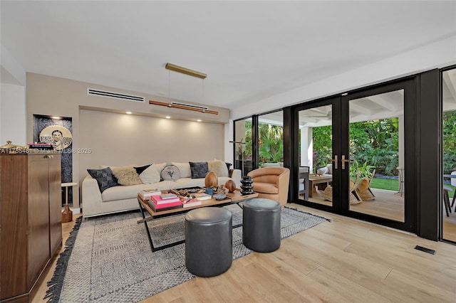 living area with french doors, light wood-type flooring, and visible vents