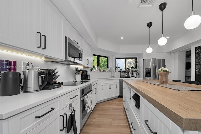 kitchen with light wood finished floors, butcher block counters, visible vents, appliances with stainless steel finishes, and white cabinets