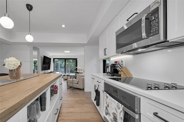 kitchen with stainless steel appliances, white cabinetry, and light wood-style floors