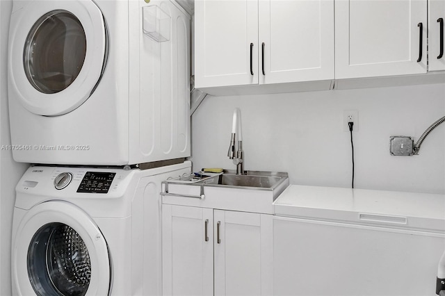 laundry room with stacked washer and clothes dryer, cabinet space, and a sink