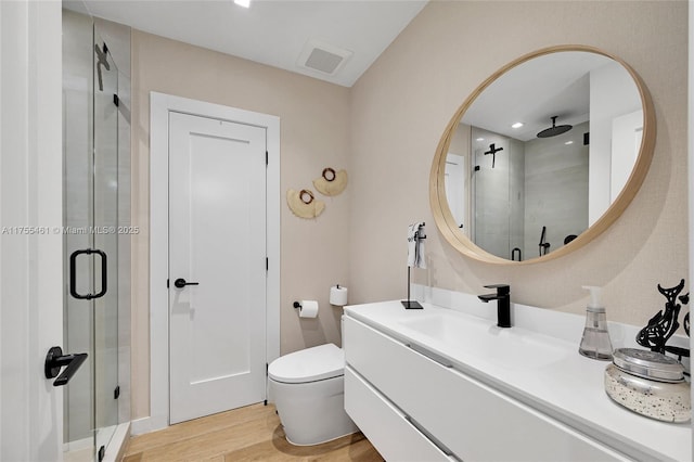 full bathroom with a stall shower, visible vents, toilet, wood finished floors, and vanity