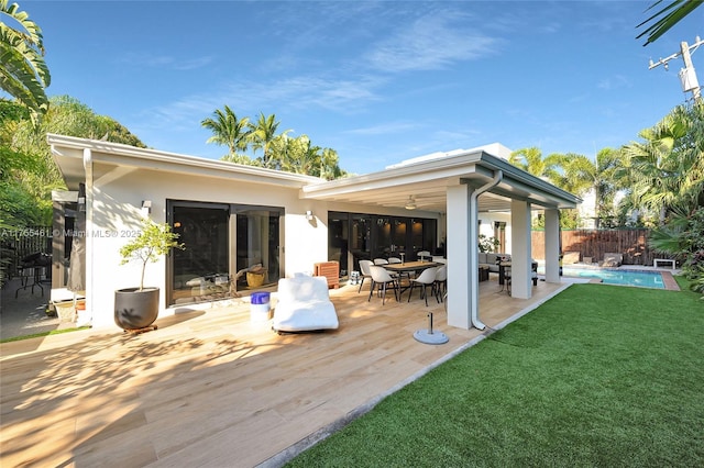 rear view of house with a fenced in pool, fence, a deck, a yard, and stucco siding