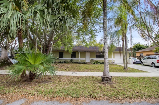 view of front of house featuring an attached garage, stucco siding, driveway, and a front yard