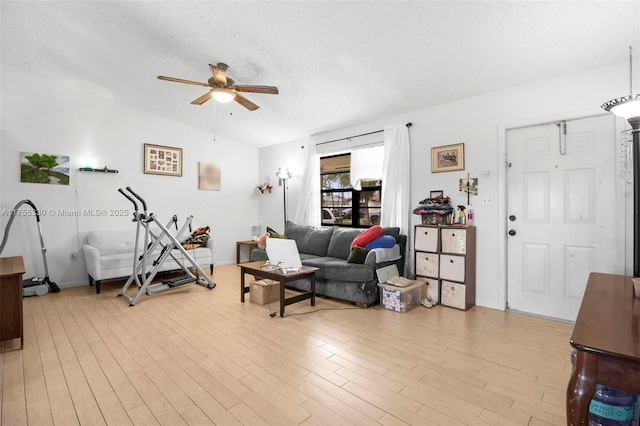 exercise room with light wood finished floors, baseboards, a ceiling fan, and a textured ceiling