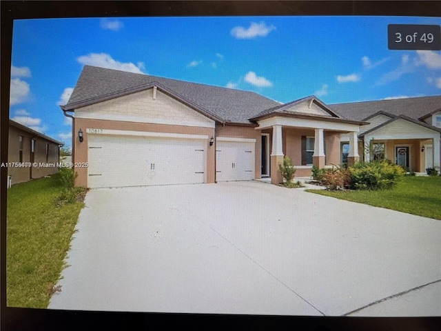 view of front of property with a porch, a front yard, driveway, and an attached garage