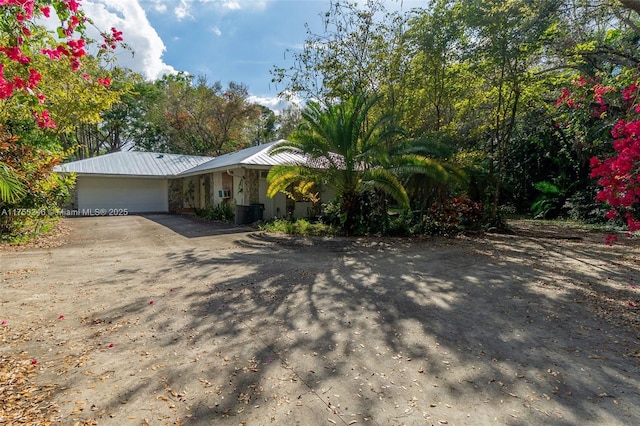 view of front of house with a garage, concrete driveway, metal roof, and stone siding