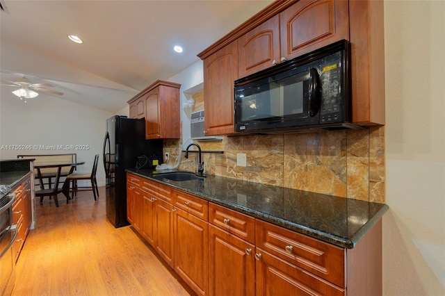 kitchen featuring lofted ceiling, a sink, light wood finished floors, black appliances, and tasteful backsplash