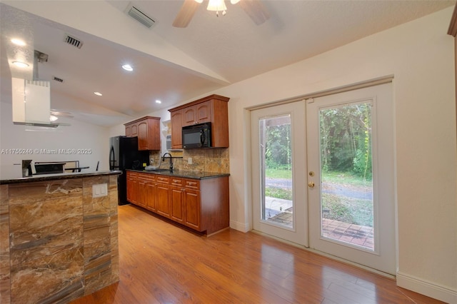 kitchen with lofted ceiling, visible vents, backsplash, a sink, and black appliances